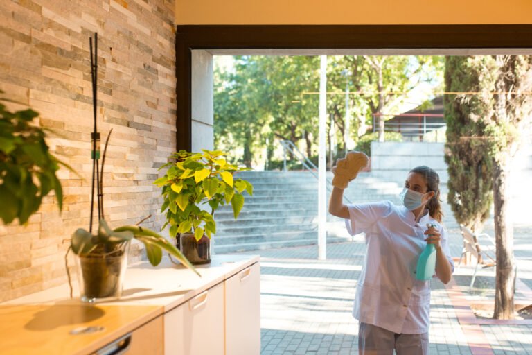 Young woman cleaning window glass outside of a spa center